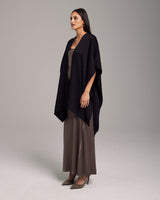 Model wearing a black solid alpaca duster over a long brown dress