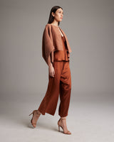 Model wearing a shimmering copper bolero over a matching outfit, standing in a neutral setting.