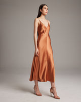Model wearing a V-neck slip dress in terracotta color