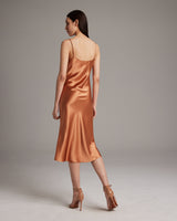 Back view of a model wearing a satin midi slip dress in terracotta