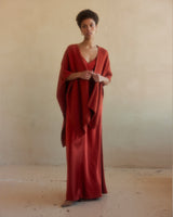Model wearing a burnt orange alpaca duster over a red dress