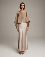 Model wearing a camel bolero over a satin slipdress