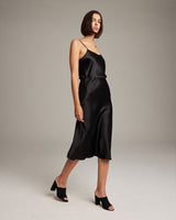 Model wearing a black Bias Midi Skirt in Silk Charmeuse with a slim fit and mid-calf length.