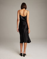 Model wearing a black Bias Midi Skirt in Silk Charmeuse from the back