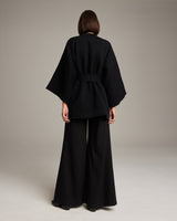 Back view of a model wearing a black Flammé Samurai Jacket with wide sleeves and a detachable belt.