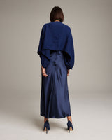 Model wearing a navy alpaca crop top over a navy satin dress from the back