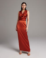 Model wearing a backless halter dress in a rich aubergine color, showcasing its elegant drape.