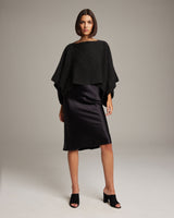 Model wearing a black alpaca crop top over a black satin dress