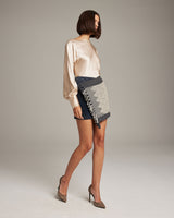 Model wearing a navy Diamante Mini Wrap Skirt with a diamond patterned textile and fringe.