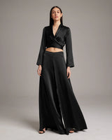 Model wearing a black silk wrap blouse and palazzo pants