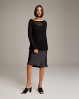 Model wearing a black Open Mesh Boatneck Sweater over a satin skirt