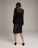 Model wearing a black Open Mesh Boatneck Sweater with a satin skirt from the back