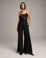 Model wearing high waist wide trousers in black, styled with a satin top.