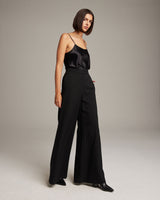 Model wearing high waist wide trousers in black, standing on a neutral background.