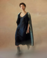 Model wearing a calf-skimming black cloak with woven linear detailing