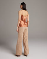 Model wearing terracotta Liquid Silk Tank with spaghetti straps and beige pants