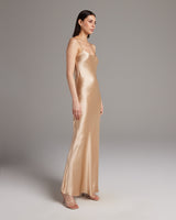 Model wearing a liquid silk slipdress in a neutral tone, showcasing its elegant drape.