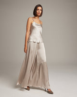 Model wearing a liquid silk tank top with spaghetti straps and a matching skirt in a neutral color.