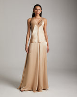 Model wearing a beige silk outfit with a flowing skirt and top