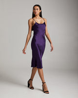 Model wearing a purple midi slip dress with spaghetti straps and heels.