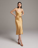 Model wearing a gold satin midi slip dress with spaghetti straps