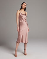 Model wearing a blush Midi Slip Dress with spaghetti straps, showcasing its satin finish.