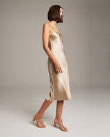Model wearing a champagne-colored VOZ midi slip dress with a sleek design.