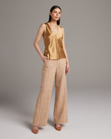 Model wearing a gold silk raw edge tank top with beige palazzo pants