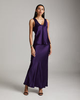 Model wearing a silk raw edge tank and matching skirt in aubergine color