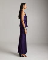 Model wearing a purple silk raw edge tank and matching skirt, side view.