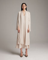 Model wearing a long, light-colored linen wrap blouse with front sashes.