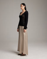 Model wearing a black sweater and beige silk palazzo pants