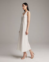 Model wearing a white linen V-neck maxi dress with straps and heels