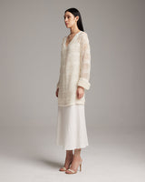 Model wearing a loose knit linen sweater in ivory, side view