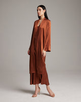 Model wearing a rust-colored Silk Featherlight Wrap Blouse, showcasing its drapey design.