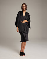 Model wearing a black silk kimono over a black dress, showcasing the garment's design.