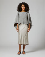 Model wearing a gray alpaca crop top with a silk skirt and sandals.