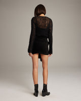 Model wearing a black sweater and Diamante Mini Wrap Skirt from the back