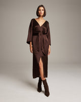 Model wearing a brown silk tunic dress with a tie at the waist and a slit.