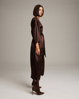Side view of a model wearing a chocolate silk tunic dress with a kimono-inspired silhouette.