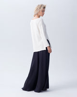 Model wearing a white Cotton Flammé Relaxed Sweater with side slits and boat neckline