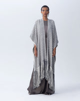 Model wearing a long chevron duster with fringe in black and ivory colors