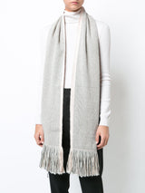 A model wearing a grey and white Lineas Fringe Scarf with fringes.