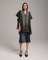 Model wearing a dark green Lineas Fringe Manta with fringes over a satin dress
