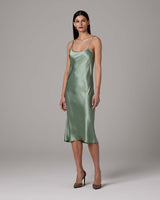 Model wearing a sage green VOZ midi slip dress with spaghetti straps