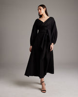 Model wearing a black Peasant Blouse Dress with a wrap silhouette and open neckline
