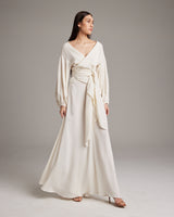 Model wearing a white peasant blouse with a wrap design and puff sleeves