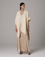 Model wearing a cream-colored alpaca duster over a satin dress