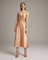 Model wearing a peach V-neck slip dress with spaghetti straps