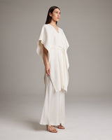 Model wearing a textured white cotton kaftan with a belt, standing against a neutral background.